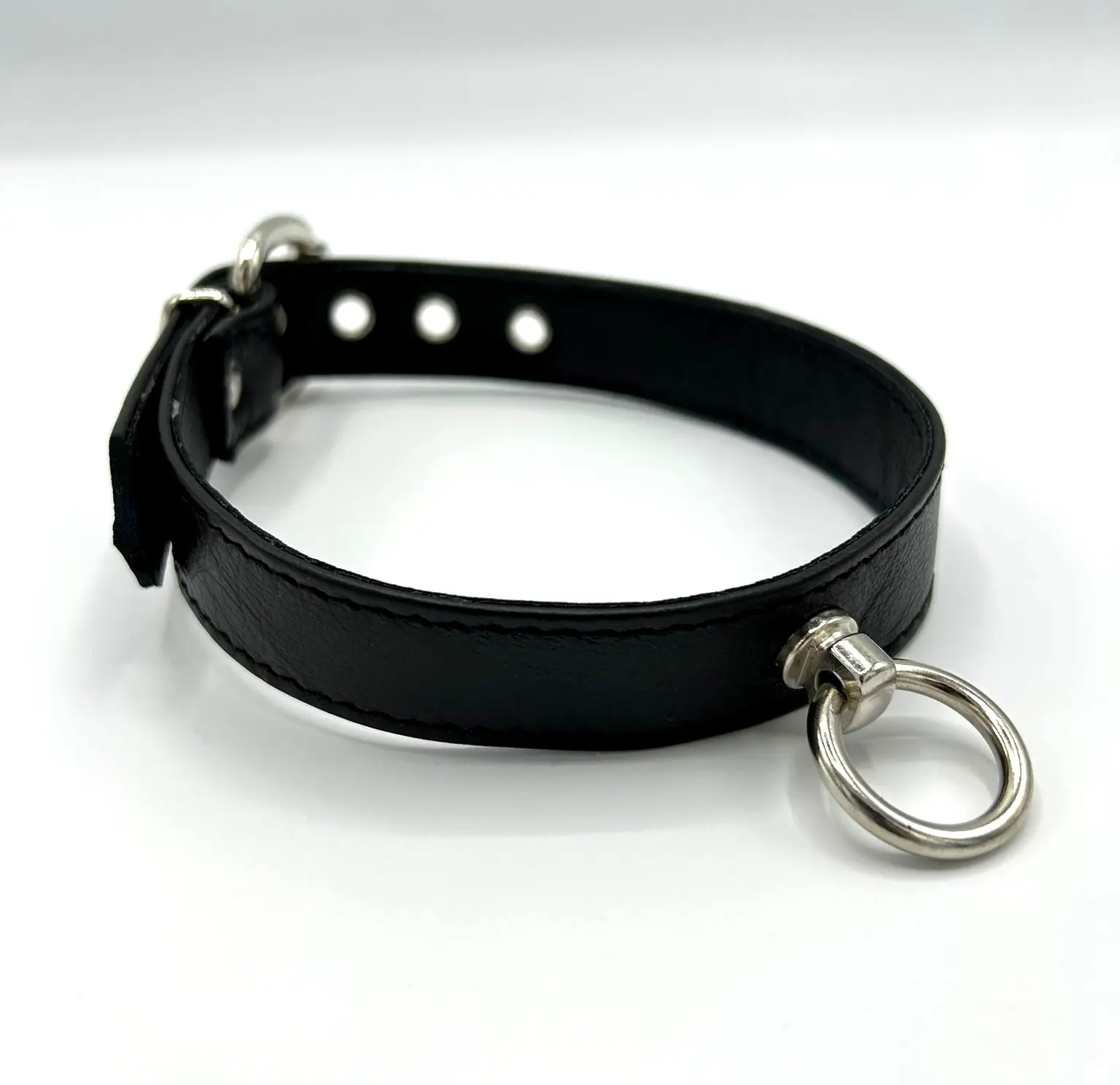 Schwarzes Halsband mit Ring der O auf weißem Hintergrund seitlich