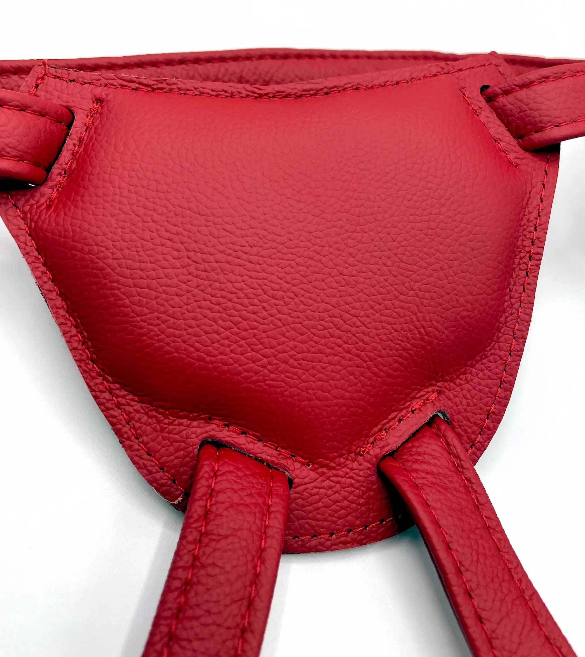 Rückseite der Frontplatte eines roten Leder-Strap-on-Harness mit gepolsterter Innenseite und angenähten Beinriemen