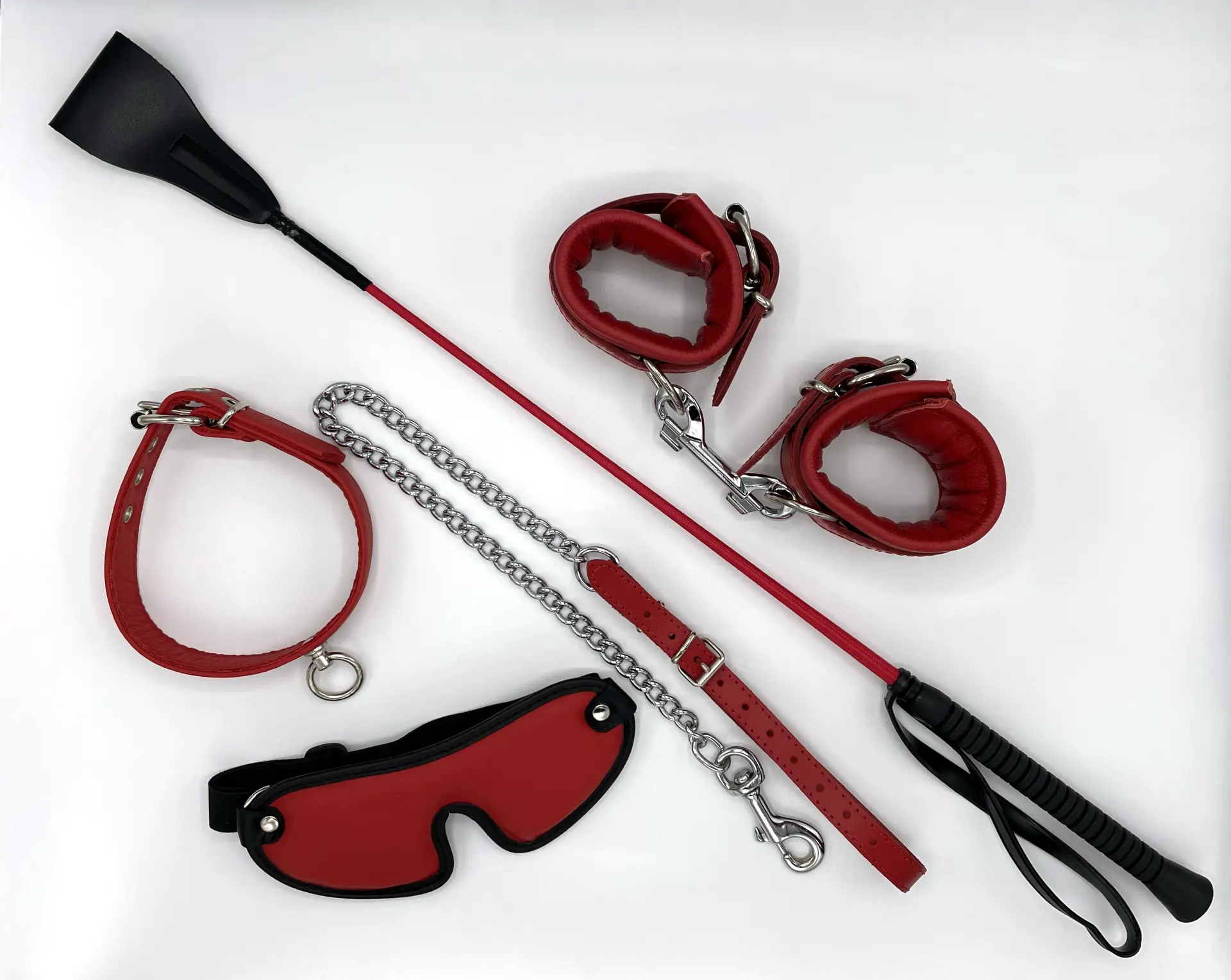 Rotes Packet aus Gerte, Augenmaske, Halsband, Handfessel und Führungsleine aus rotem Leder